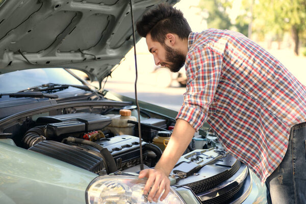 man looking under car hood