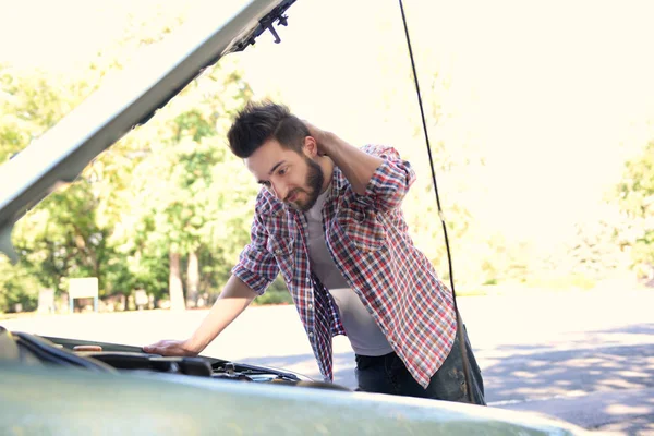 男は車のフードの下で探して — ストック写真