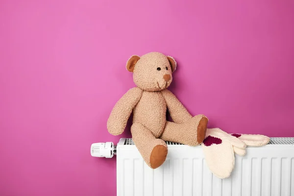 Urso de pelúcia com luvas no radiador de aquecimento — Fotografia de Stock