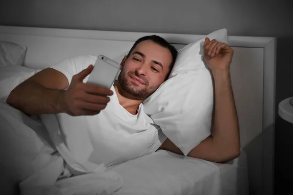 Hombre con smartphone en la cama —  Fotos de Stock