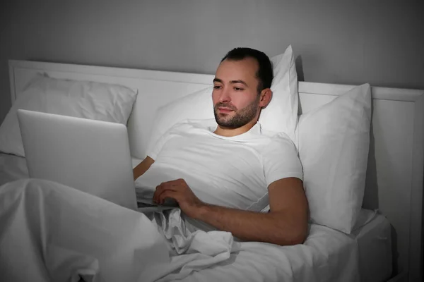 Hombre con portátil en la cama — Foto de Stock