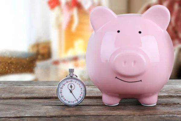 Holiday expenses concept. Piggy bank with stopwatch on wooden table — Stock Photo, Image