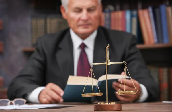 Schalen van Justitie op houten tafel en mannelijke advocaat op achtergrond — Stockfoto