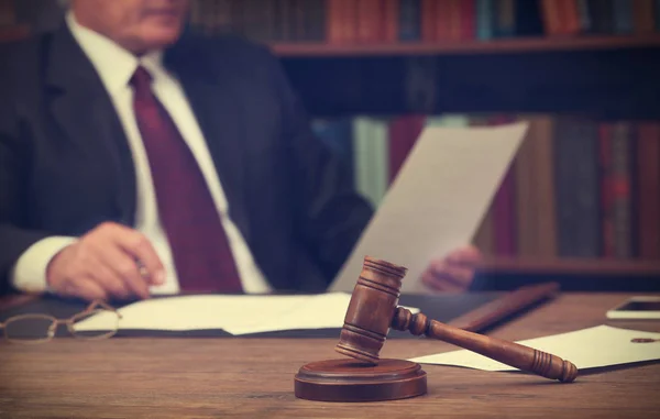 Bruin van de hamer op de houten tafel en mannelijke advocaat op de achtergrond, close-up — Stockfoto