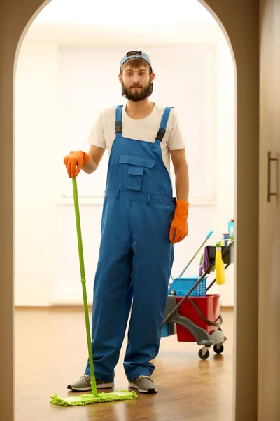 Lustiger junger Mann wischt Boden in leerer Wohnung — Stockfoto