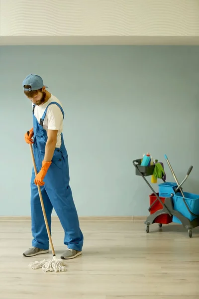 Funny young man moping floor in empty flat — Stock Photo, Image