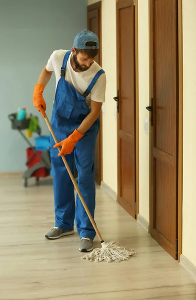 Engraçado jovem homem esfregando chão em apartamento vazio — Fotografia de Stock