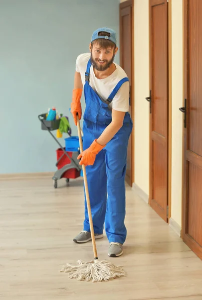 Lustiger junger Mann wischt Boden in leerer Wohnung — Stockfoto