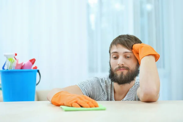 Divertente giovane uomo pulire mobili con tovagliolo a casa — Foto Stock