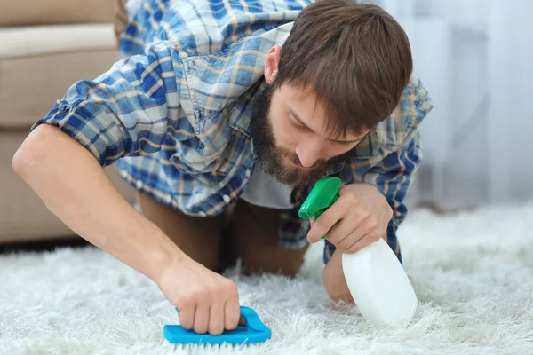 Αστεία νεαρός άνδρας τον καθαρισμό ταπήτων στο σπίτι — Φωτογραφία Αρχείου
