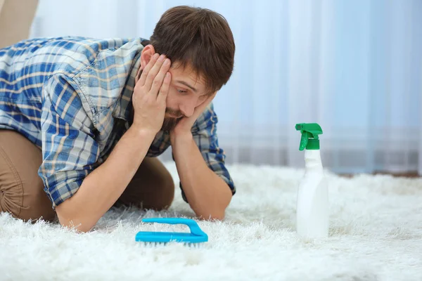 Rozpaczliwej młody człowiek, czyszczenie dywanów w domu — Zdjęcie stockowe
