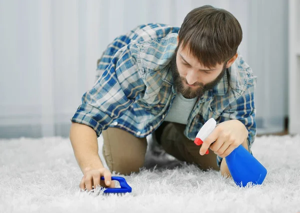 Divertente giovane uomo pulizia tappeto a casa — Foto Stock