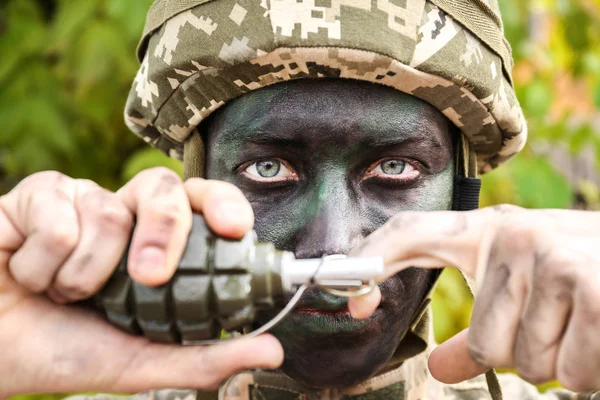 Vista de perto do soldado puxando pino de segurança da granada de fragmentação, no fundo verde desfocado — Fotografia de Stock