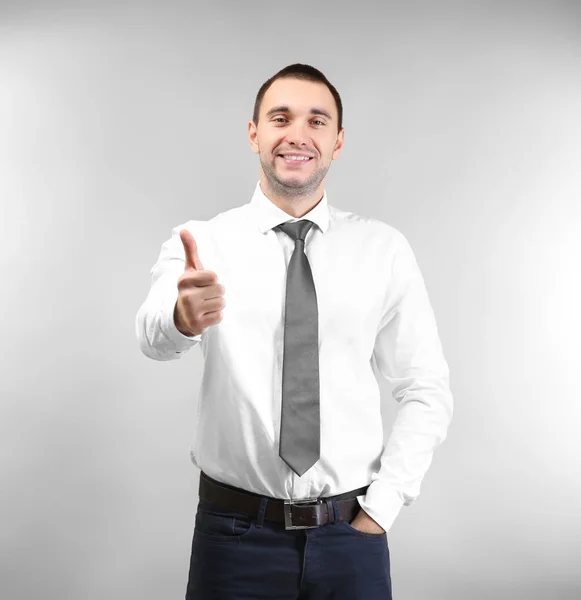 Handsome man showing thumb up sign, on light background — Stock Photo, Image