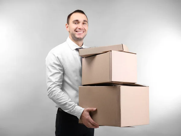 Beau homme avec des boîtes en carton sur fond clair — Photo