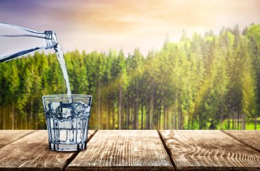 Doğa arka plan üzerinde cam içine temiz su dökme