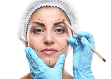 Surgeon drawing marks on female face against white background. Plastic surgery concept clipart