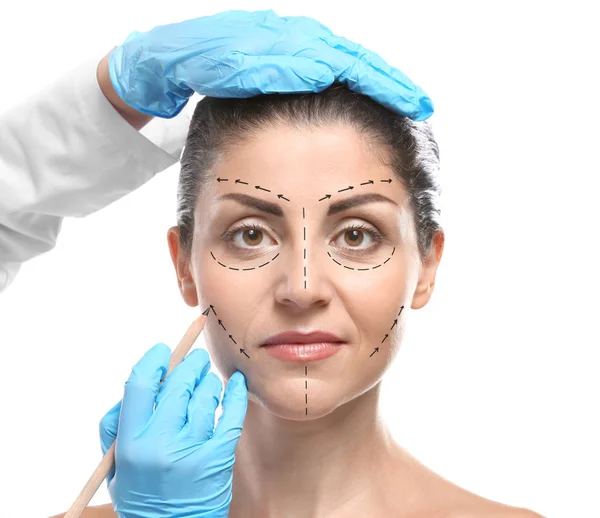 Surgeon menggambar tanda pada wajah perempuan terhadap latar belakang putih. Konsep pembedahan plastik — Stok Foto