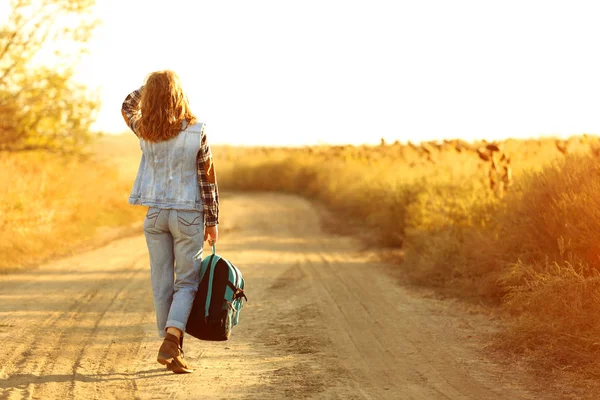 Mujer joven con mochila caminando por el camino del campo —  Fotos de Stock