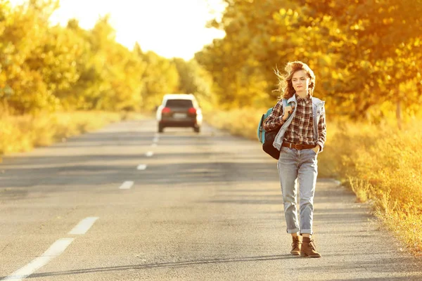 Молодая женщина с рюкзаком на дороге — стоковое фото