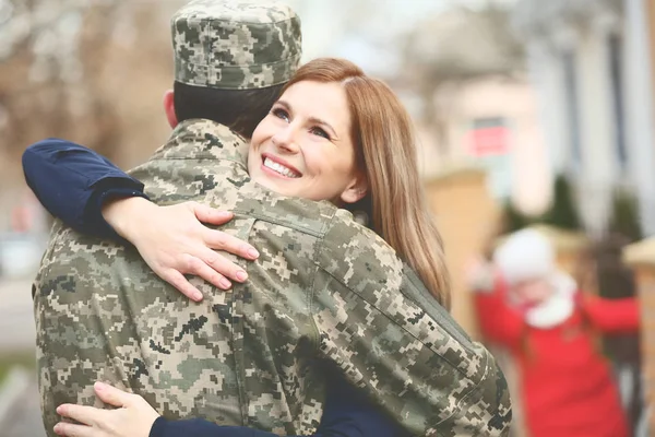 Soldado em camuflagem abraçando sua esposa ao ar livre — Fotografia de Stock