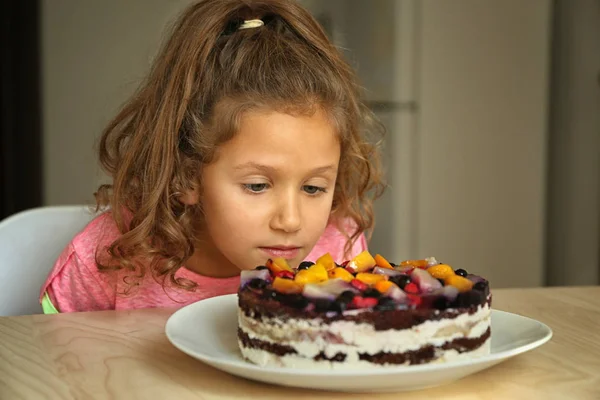 Милая Маленькая Девочка Смотрит Вкусный Торт Оставленный Кухонном Столе — стоковое фото