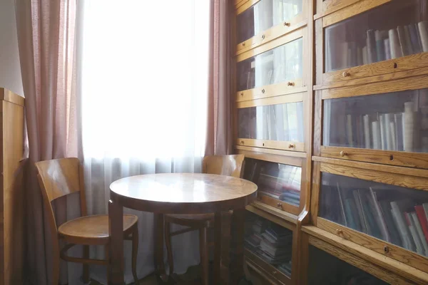 Wooden table and glass bookcase — Stock Photo, Image