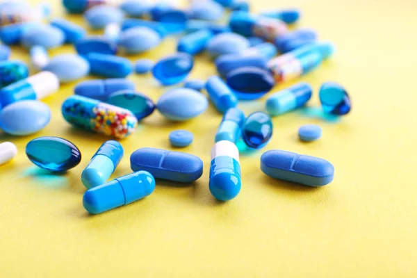 Heap of pills on yellow table — Stock Photo, Image