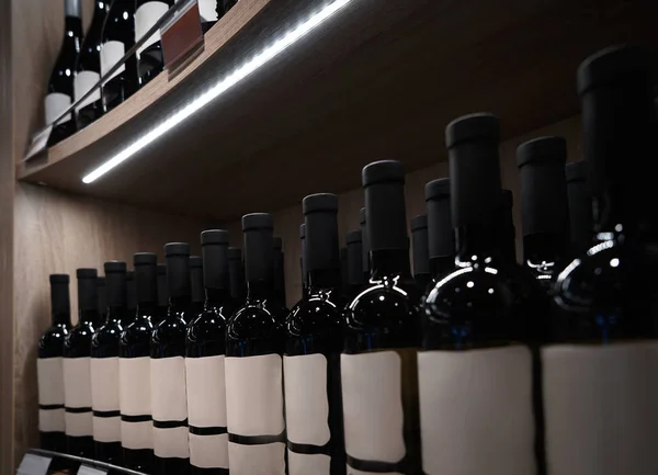 Garrafas de vinho na prateleira de madeira — Fotografia de Stock