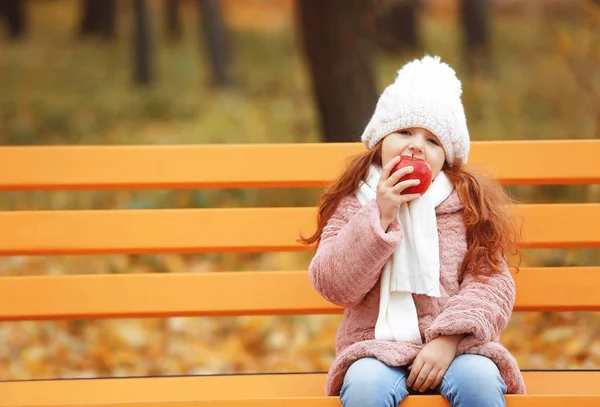 Girl eating apple on bench — Stock Photo, Image