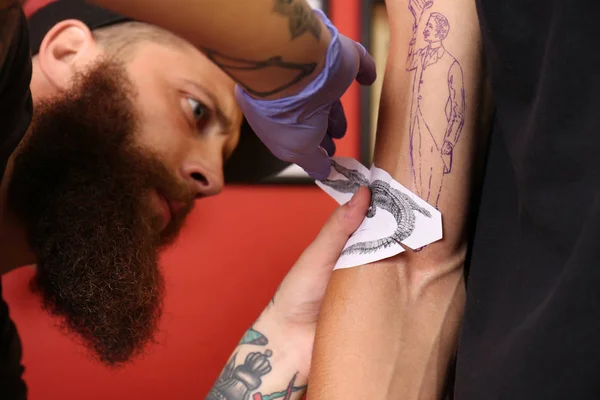纹身大师在演播室应用剪影到男性胳膊 关闭看法 — 图库照片
