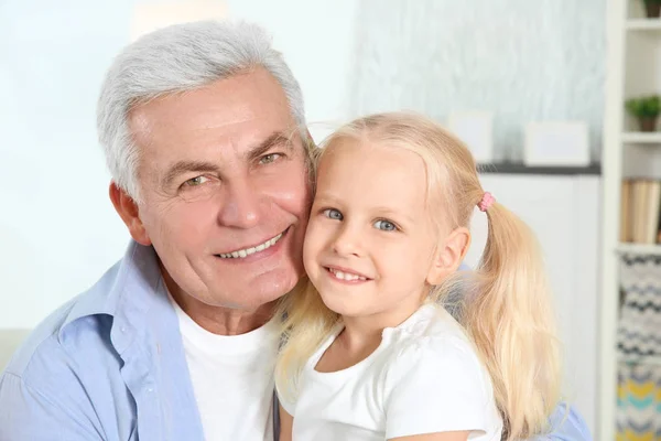Милая маленькая девочка с дедушкой в гостиной — стоковое фото