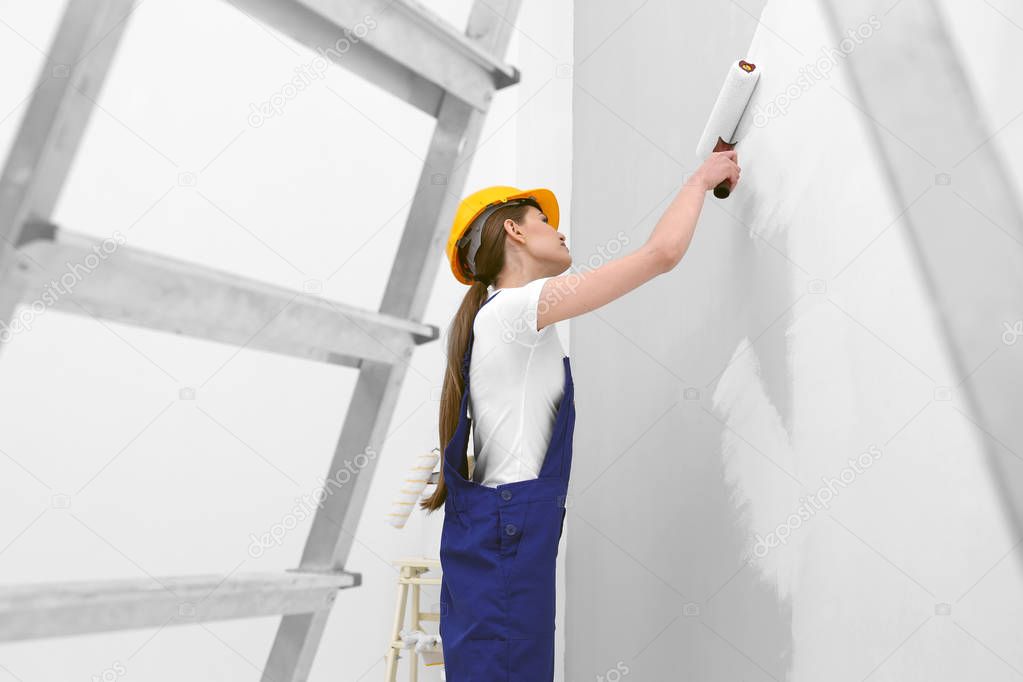 Young worker painting wall