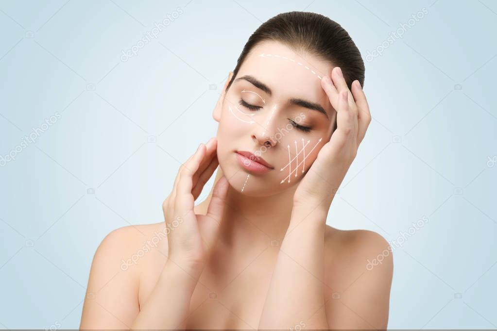 Plastic surgery concept. Young woman with marks on face against blue background