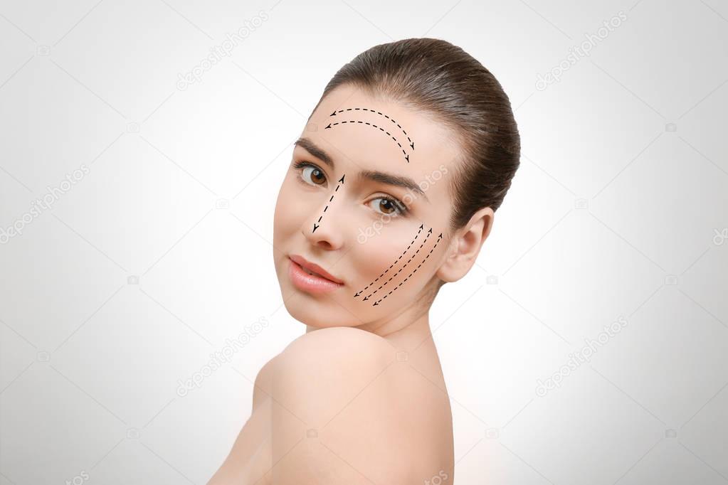 Plastic surgery concept. Young woman with marks on face against light background
