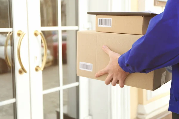 Courier with parcels on doorstep — Stock Photo, Image