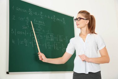 Yazı tahtası beyaz arka plan üzerinde yanında işaretçisiyle genç öğretmen