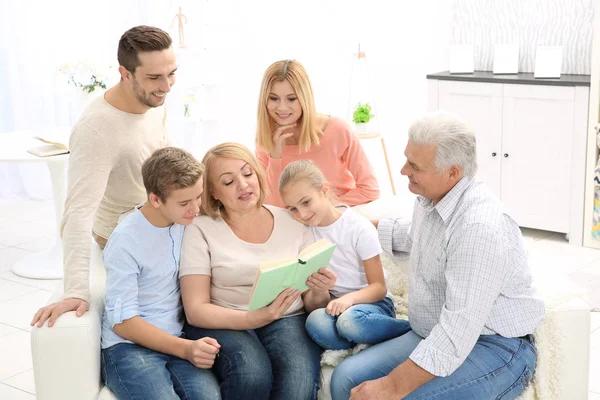 Oturma odasında kanepede otururken mutlu aile okuma kitabı