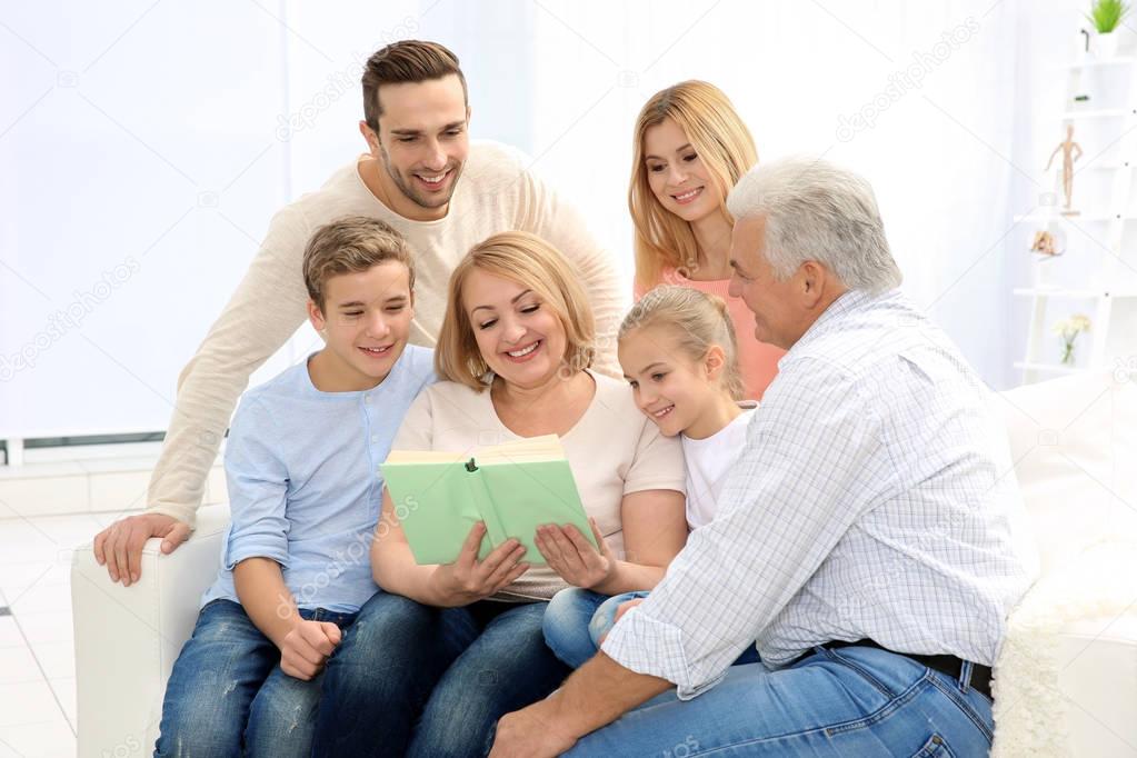 Happy family reading book while sitting on sofa in living room