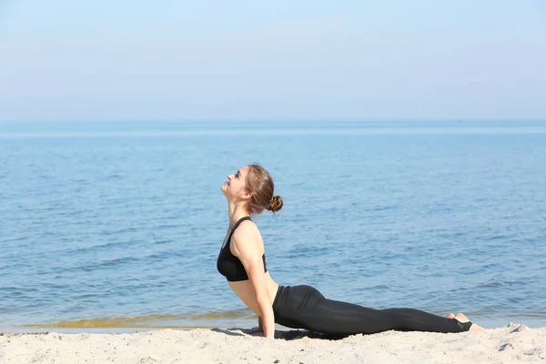 Mujer haciendo yoga por mar — Foto de Stock