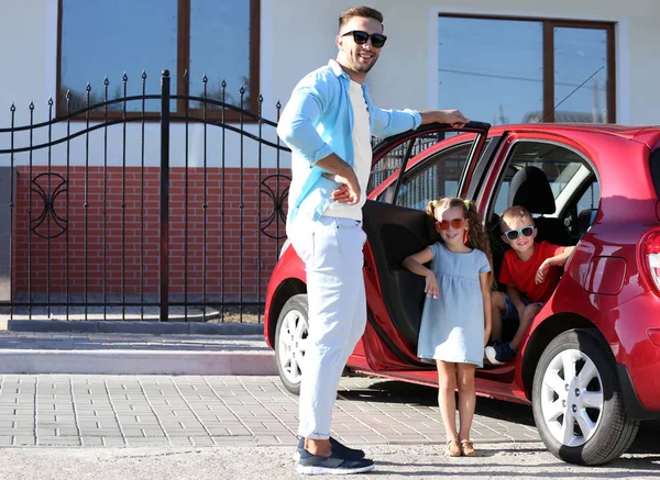 Щаслива сім'я біля своєї машини в сонячний день — стокове фото