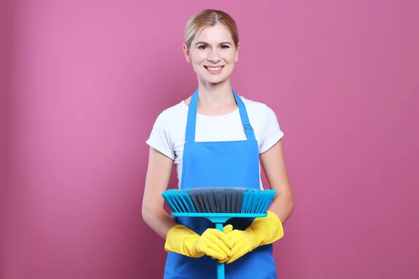Hübsche erwachsene Frau mit Bodenbürste auf farbigem Hintergrund — Stockfoto