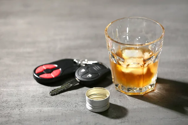 Kaca dengan alkohol dan kunci mobil di meja abu-abu — Stok Foto