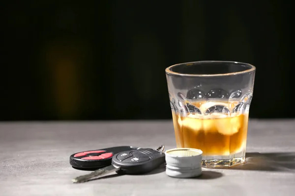 Glass with alcohol and car keys on grey table — Stock Photo, Image