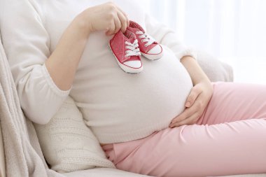 pregnant woman holding baby shoes clipart