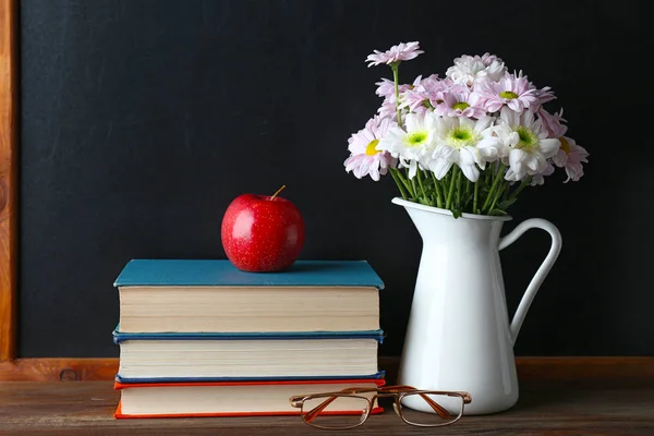 Ramo de flores, libros con manzana y vasos — Foto de Stock