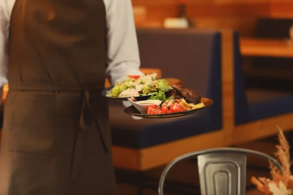 Waiter holding plates with tasty dishes