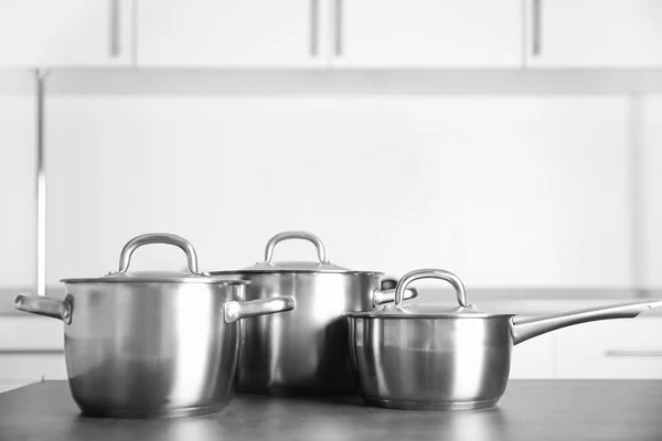 RVS steelpannen op tafel — Stockfoto