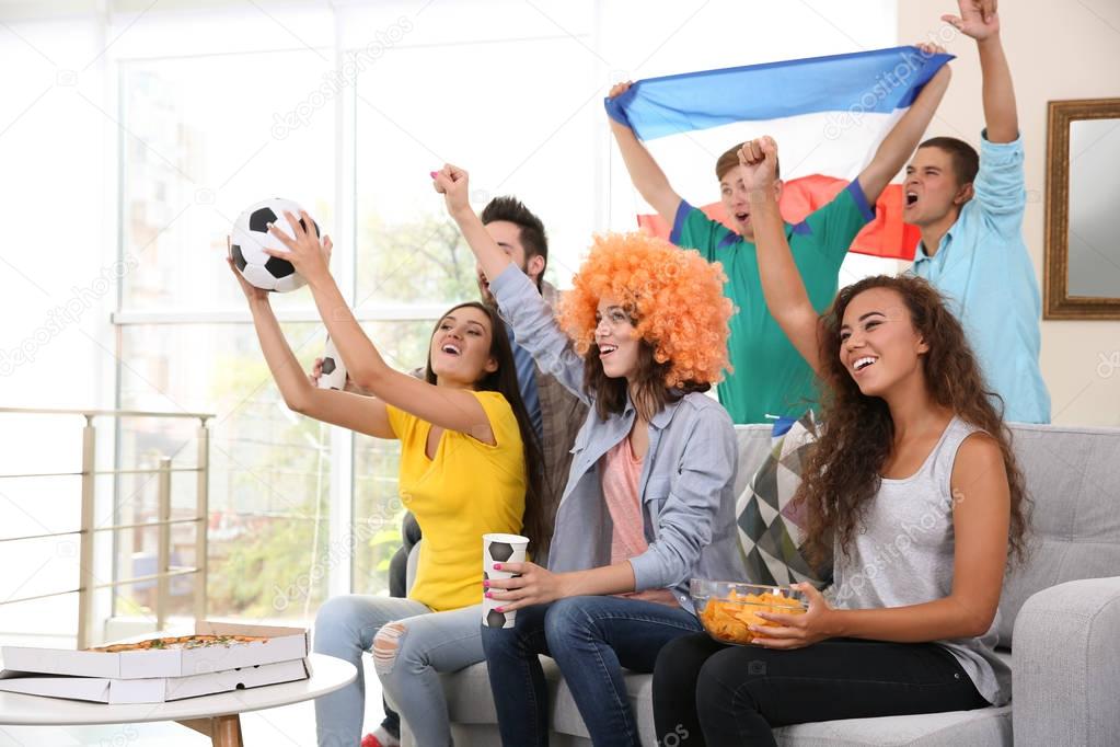 Soccer fans with France flag emotionally watching game in the room