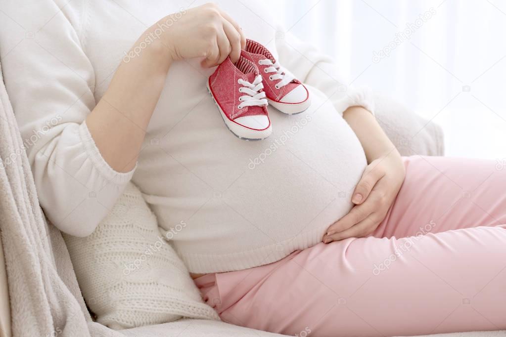 pregnant woman holding baby shoes